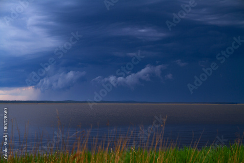 Dramatic stormy sky over the lake with grass in foreground
