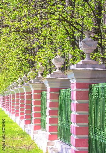 The ancient fence of the park with stone flowerpots