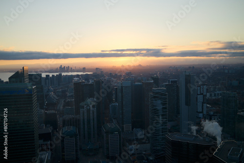 Urban skyline at sunset reflecting on water with cloudy orange sky