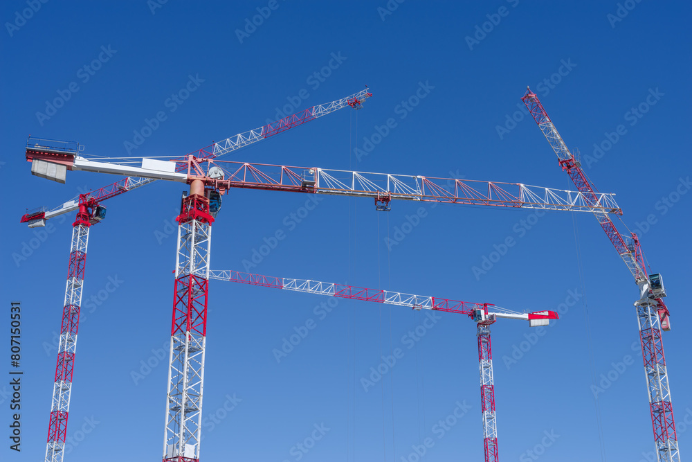 Construction cranes in front of the blue sky at a large construction site Construction cranes in front of the blue sky at a large construction site