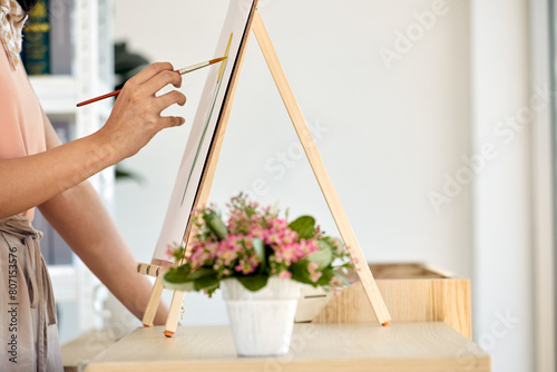 Drawing inspiration from vibrant bouquet, focused female artist paints floral composition on canvas using brush
