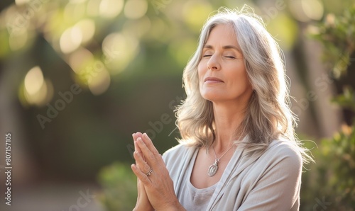Beautiful grey haired mid-aged woman meditating in nature