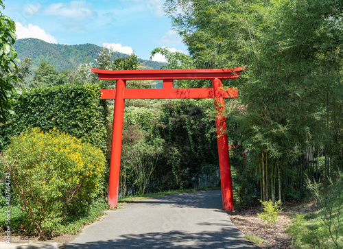 Single Japanese spiritual  traditional red pole with the bamboo tree and the Other tree  in the garden at noon time.