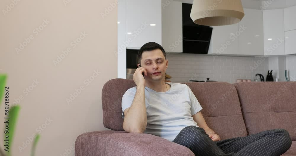 Caucasian man using phone while sitting on sofa at home Caucasian man using phone while sitting on sofa at home