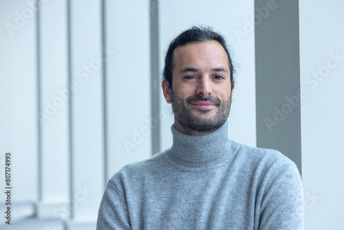 portrait d'un beau jeune homme de 35 ans souriant et pensif. C'est un employé qui pose dans les bureaux de son entreprise