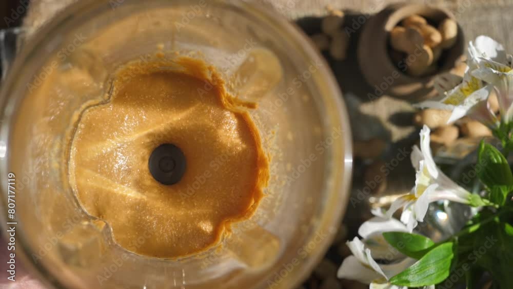 Top view grind the peanuts using a blender to a paste to get peanut butter. The process of preparing peanut butter using a blender illuminated by the sun's rays