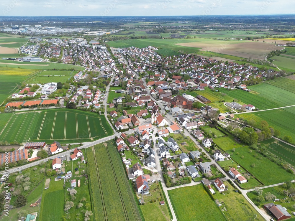 Drohnenaufnahme von einem idyllischen Dorf im Alb-Donau-Kreis mit  großem Industriegebiet im Hintergrund