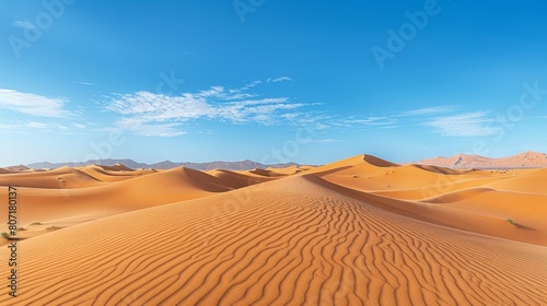 A serene desert landscape with rolling sand dunes and a clear blue sky