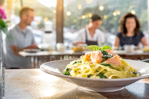 Tagliatelle mit Lachs und Spinat, im Hintergrund ein Restaurant 