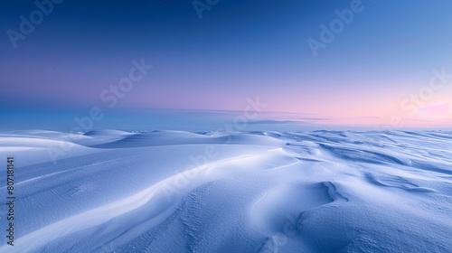 Banner format of a winter evening with light snow falling gently over smooth snowdrifts  the sky a deep shade of twilight blue  with copy space