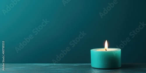 Teal background with white thin wax candle with a small lit flame for funeral grief death dead sad emotion with copy space texture for display products 