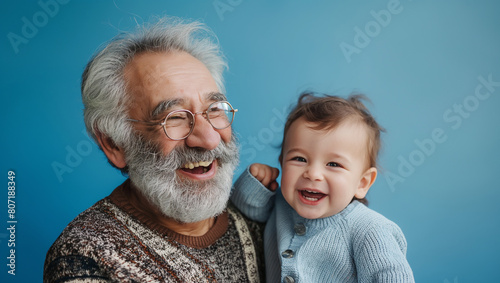 Old man and young kid laughing together happy family generations on blue studio background 