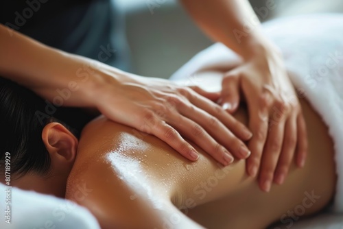 Detail of professional hands performing a shoulder massage on a young woman at a modern spa