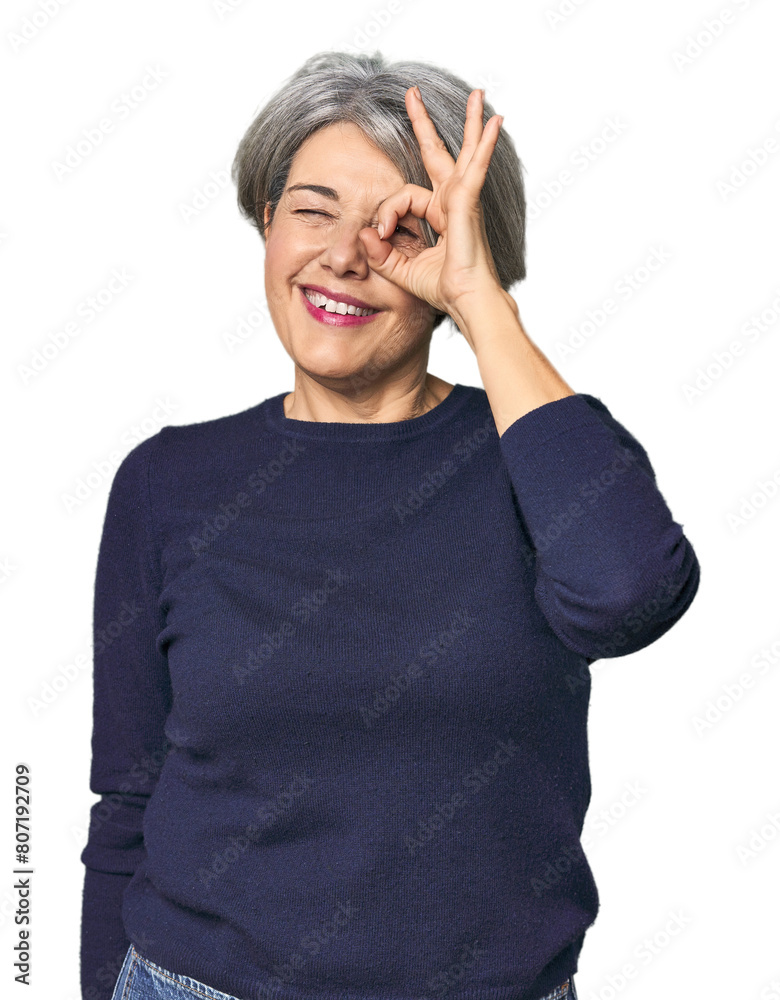 Caucasian mid-age female on studio background excited keeping ok gesture on eye. Caucasian mid-age female on studio background excited keeping ok gesture on eye.