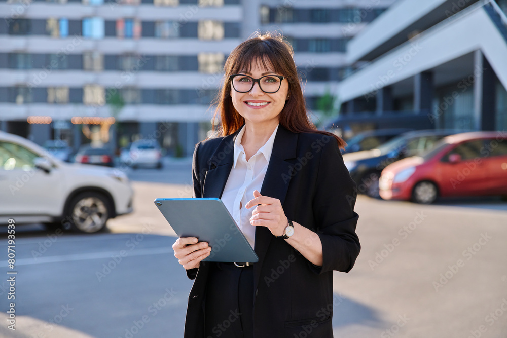 Mature confident business woman with digital tablet in black suit outdoors Mature confident business woman with digital tablet in black suit outdoors
