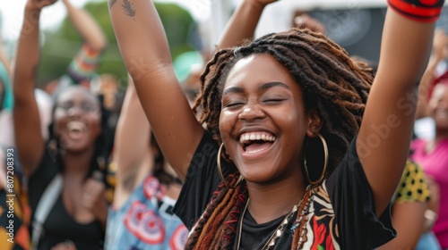 A woman with dreadlocks smiles joyfully, raising her arms in celebration on Juneteenth