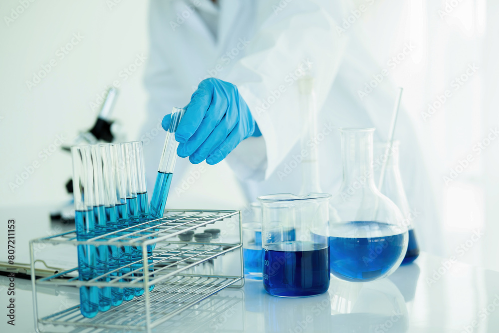 Medical or scientific researcher or man doctor looking at a test tube of clear solution in a laboratory Medical or scientific researcher or man doctor looking at a test tube of clear solution in a laboratory