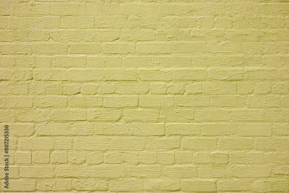 Fototapeta premium The brick wall is painted with yellow paint. Abstract construction background.