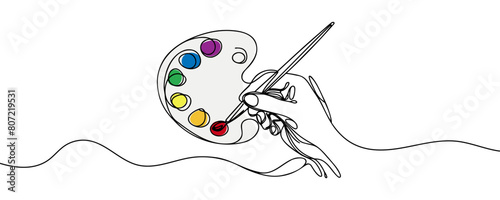 palette with paints and a hand with a brush drawn one line on a white background.