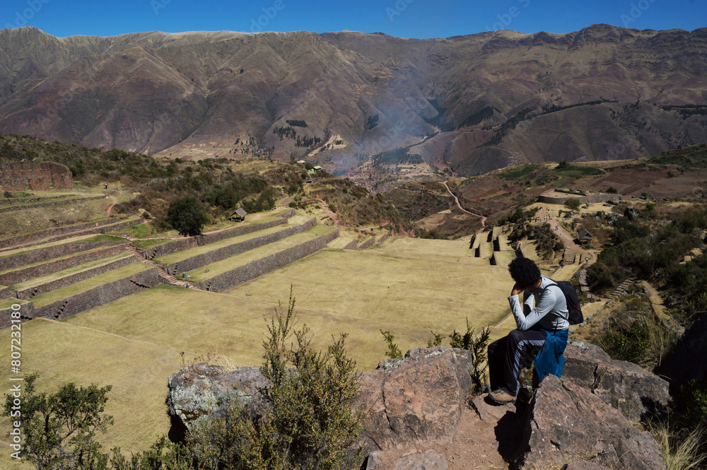 Young man sitting on stone observing landscape Young man sitting on stone observing landscape