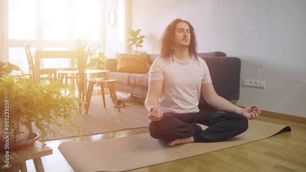 Young male with long hair meditating at home Young male with long hair meditating at home