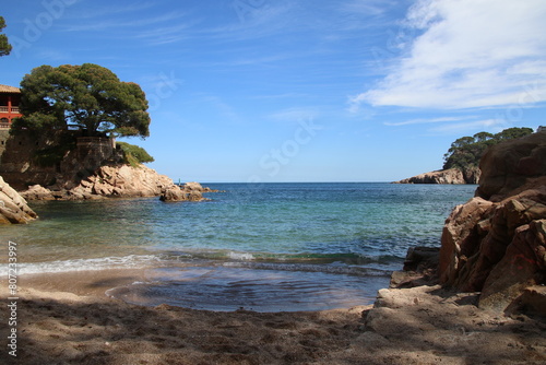 Natural and small coves of the Costa Brava with boats in the background and the blue sky with clouds and blue water. A beautiful place for vacations.