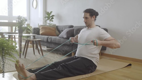 Workout at home concept. Young male doing rows with bands