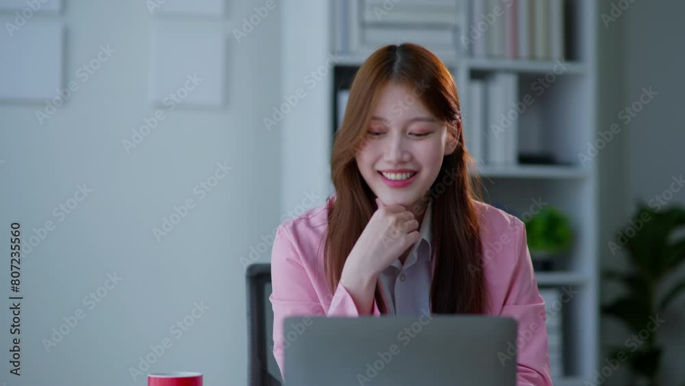Businesswoman in pink suit turn on working and typing on laptop in office space with happy face Businesswoman in pink suit turn on working and typing on laptop in office space with happy face