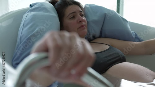 Pregnant woman inside bathtub preparing for childbirth experiencing contractions and pain beofore giving birth, maternal care at clinic engulfed by water