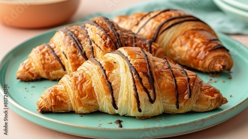  Croissants topped with melted chocolate sit alongside a bowl