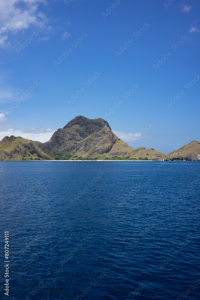 Majestic mountain peaks tower over the serene blue waters near Komodo Island, a gem in Indonesia's archipelago