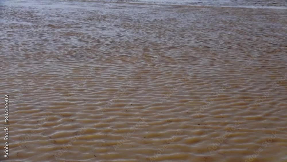 Long shot of an accumulation of muddy floodwater, swirling and churning as it flows in one axis. Long shot of an accumulation of muddy floodwater, swirling and churning as it flows in one axis.