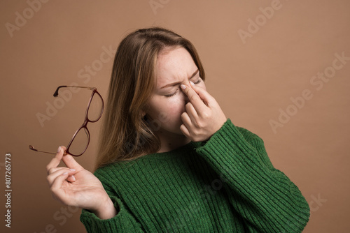 woman with poor vision on a isolated beige background, health problems astigmatism myopia