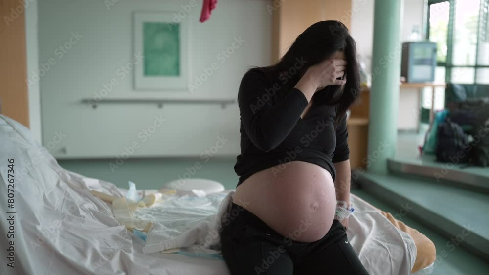 Pregnant woman suffering from contractions during pre labor at clinic covering face in pain, expecting mother at hospital waiting for childbirth