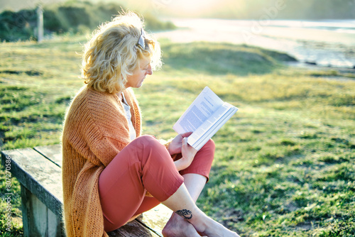 Young mature blonde woman reading outdoor.