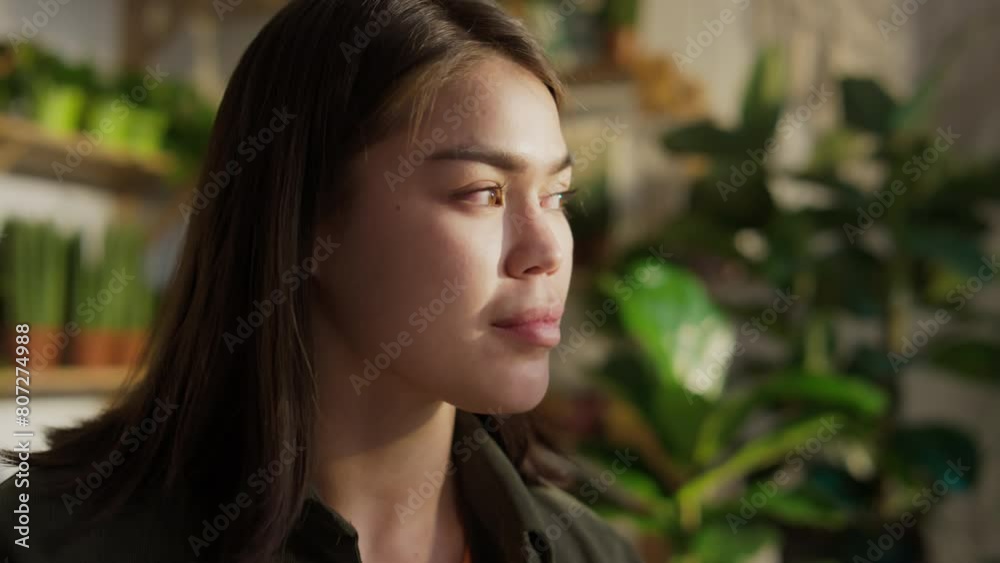 Close-up of face of pensive, dreamy young Caucasian woman with dark hair relaxing in green coworking among foliage, reading book, glancing away, smiling, in natural light on sunny day Close-up of face of pensive, dreamy young Caucasian woman with dark hair relaxing in green coworking among foliage, reading book, glancing away, smiling, in natural light on sunny day