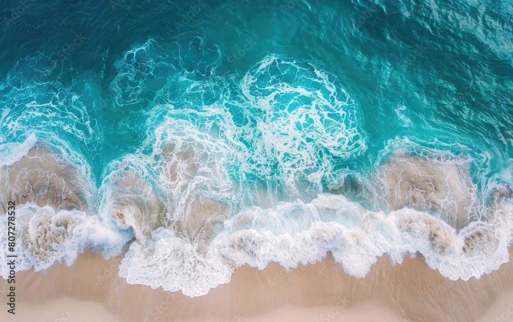 Aerial view of turquoise ocean waves meeting sandy shore.