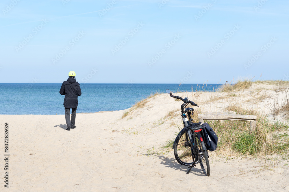 Fototapeta premium Sand dunes with beach grass at Baltic Sea near the town of Kuehlungsborn with a view of the blue sea and blue sky on a sunny day