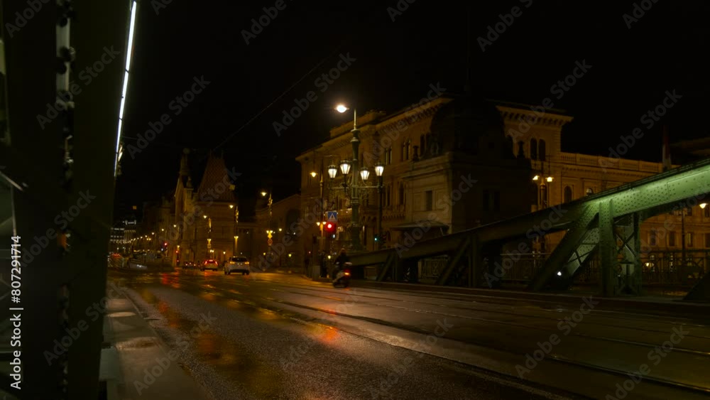 Green bridge with public traffic during night. A view of cars crossing the bridge against Europe city during night time. Green bridge with public traffic during night. A view of cars crossing the bridge against Europe city during night time.