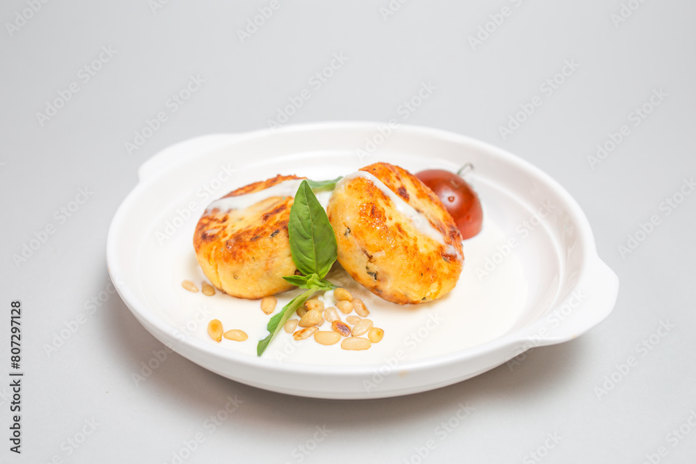 Fried cheese pancakes with sour cream and cherry tomatoes on white plate