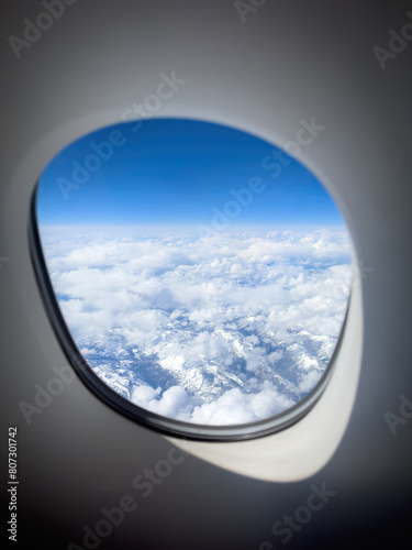 Aerial of snowcapped mountains in eastern Canada under cloudy sky seen through an aiplane window