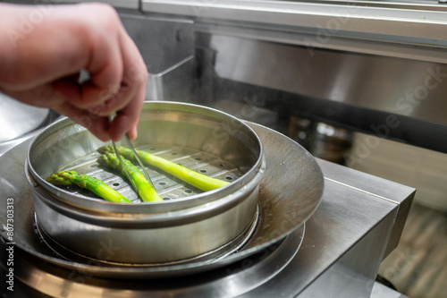 chef cooking steaming green asparagus in a steamer 