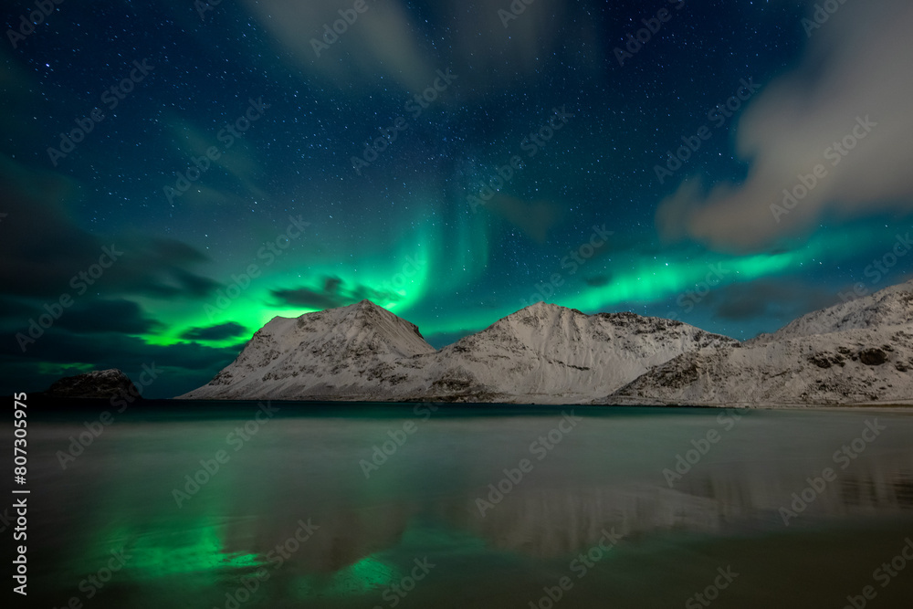 Night sky with northern lights and clouds at Haukland Beach, Lofoten Islands, Norway