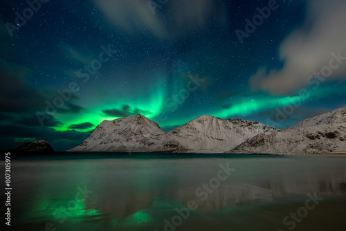Night sky with northern lights and clouds at Haukland Beach, Lofoten Islands, Norway
