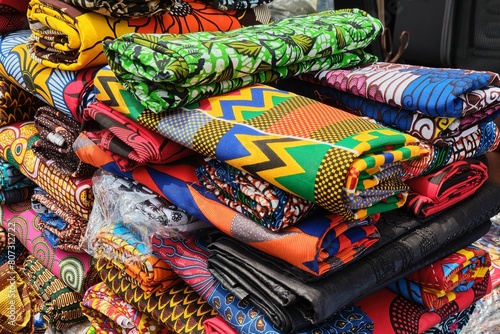 Close up of folded brightly multi coloured and patterned African Ghanaian traditional cotton print cloths