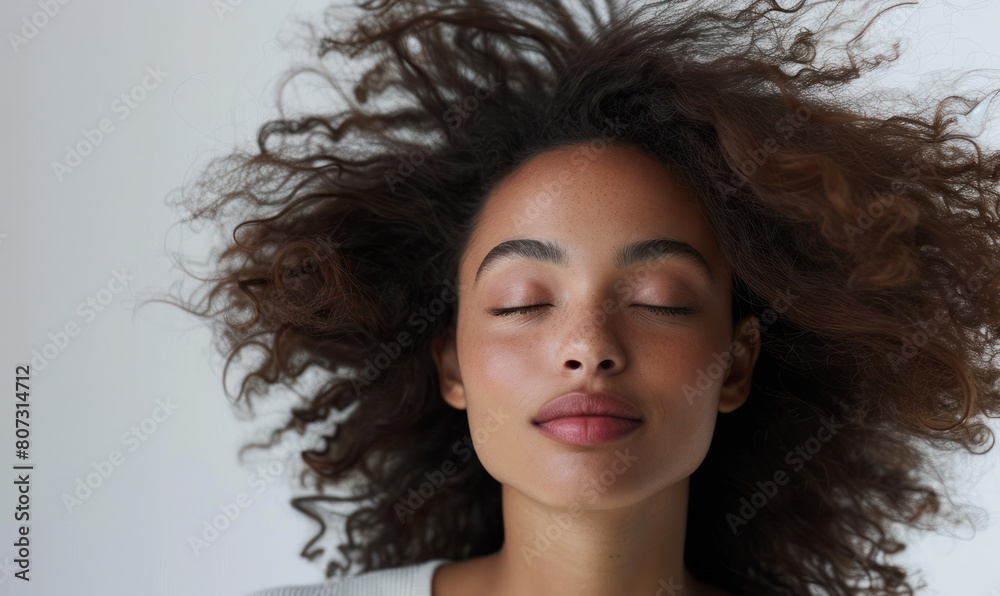 An African American woman standing with her eyes closed while her hair blows in the wind An African American woman standing with her eyes closed while her hair blows in the wind