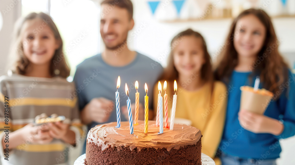 A group of individuals standing around a birthday cake with glowing candles, preparing to celebrate a special occasion