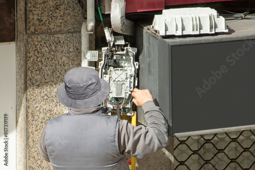 electrician worker install optical fiber cable for internet and telephone  lines  in city street photo