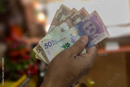 Money from Colombia, Man holding peso bills in front of him, Business investments, Creative financial concept
