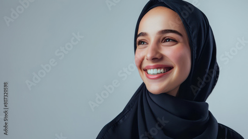 A positive Muslim woman wearing a traditional headscarf smiles happily at the camera photo